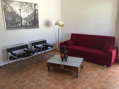 ein Wohnzimmer mit einem roten Sofa und 2 Stühlen in der Unterkunft Casa Vacanza CIVICO 33 in Marittima