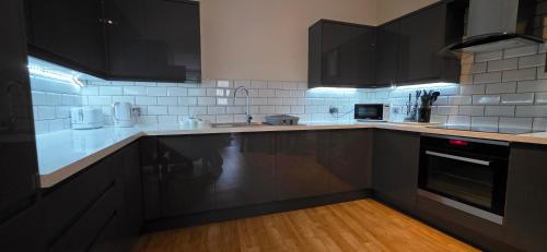 a kitchen with black cabinets and white appliances at Modern 2 bedrooms apartment in Town centre in Ipswich