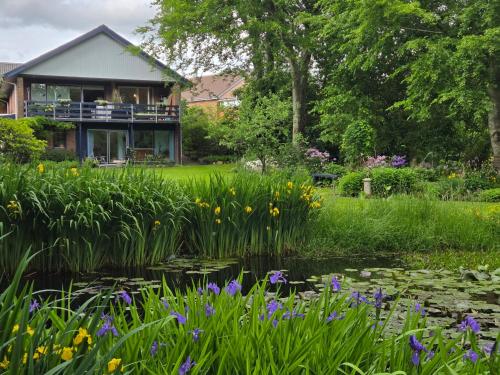 a garden with a pond and flowers in front of a house at Oasen - hyggelig lejlighed in Videbæk