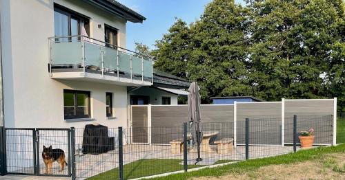 un perro parado junto a una valla delante de una casa en GreenHolidays, en Wellendingen
