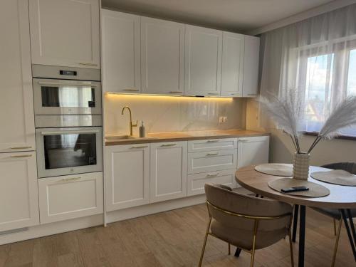 eine Küche mit weißen Schränken und einem Tisch mit einer Vase in der Unterkunft Apartamenty Biała Grań in Zakopane