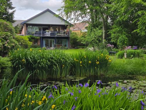a house in a garden with a pond and flowers at Oasen - hyggelig lejlighed in Videbæk