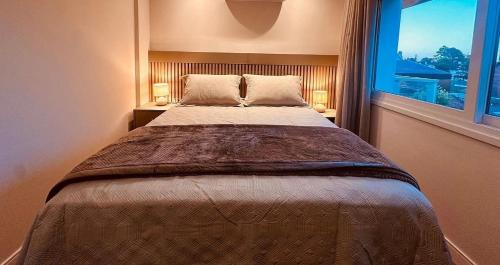 a bedroom with a large bed with a window at Apartamento frente Av Osvaldo Aranha Centro Canela in Canela