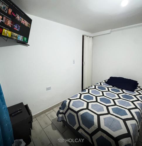 a bedroom with a bed and a white wall at Hospedaje Holcay in Bogotá