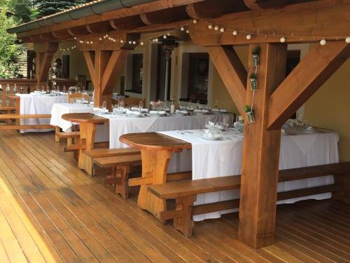 a restaurant with wooden tables with white tablecloths at Selský Dvůr Perštejn in Pürstein