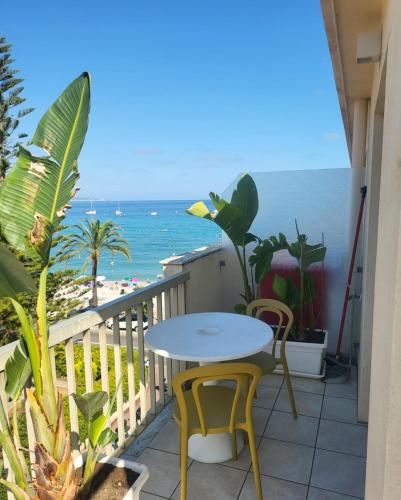 een balkon met een tafel en stoelen en het strand bij Sea Front Madame blue 4-star two-room in ecological health design in Roquebrune-Cap-Martin