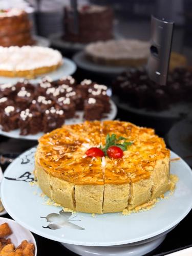 a cake on a plate on a table with other cakes at Hotel Valerim Itajaí / Navegantes in Itajaí