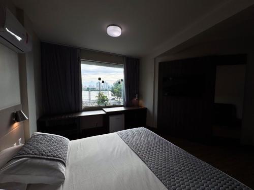 a bedroom with a large bed and a window at Hotel Valerim Itajaí / Navegantes in Itajaí