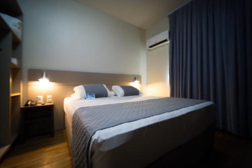 a bedroom with a large bed in a room at Hotel Valerim Itajaí / Navegantes in Itajaí