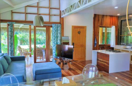 a living room with a blue couch and a tv at Fox & The Firefly Cottages in Loboc