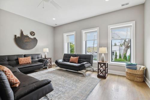 a living room with black leather furniture and windows at 2mi Downtown Hot Tub Balcony 4 King Beds in Nashville