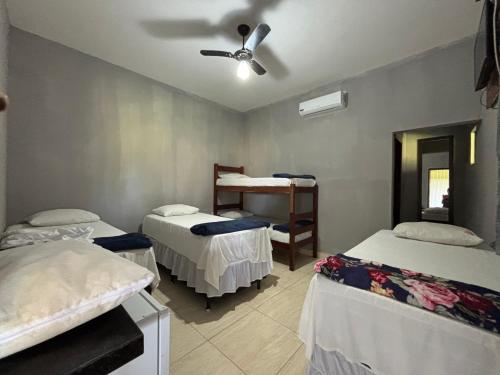 een kamer met 3 bedden en een plafondventilator bij Pousada Meu Xodó in São Miguel dos Milagres