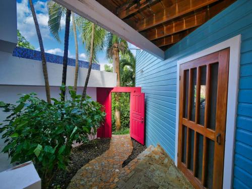 a blue house with a red door and palm trees at Private Hilltop Home Located Overlooking Roatans Beautiful Turquoise Reef, in Sandy Bay
