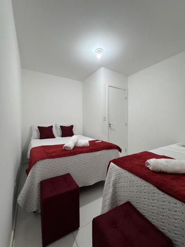 a white room with two beds with red and white sheets at Arruda Climatizada 3 Prox ao Shopping Boulevard in Vitória da Conquista