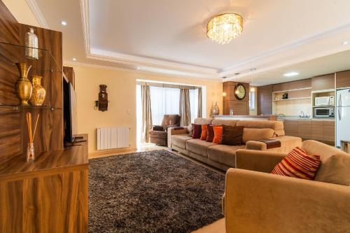 Una sala de estar con un sofá y un televisor. en Rosa Residencial Celita Pascoal, en Gramado