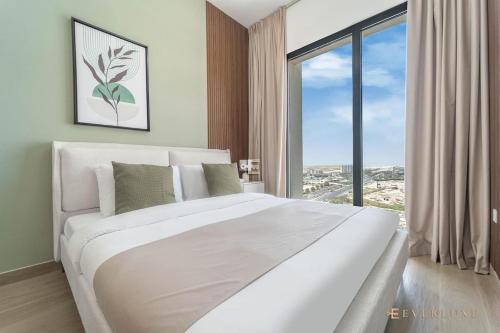 un lit blanc dans une chambre avec une grande fenêtre dans l'établissement Chic Liva 1br Family-friendly Great Amenities, à Nadd Shubayḩ