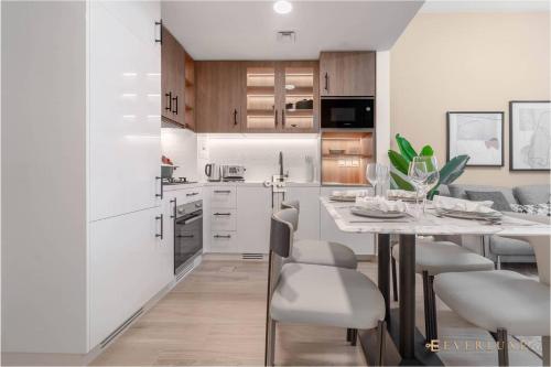 - une cuisine blanche avec une table à manger et des chaises dans l'établissement Chic Liva 1br Family-friendly Great Amenities, à Nadd Shubayḩ