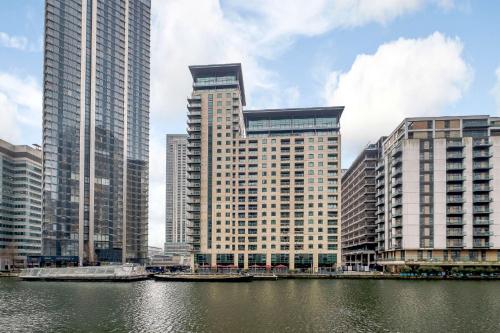 a group of tall buildings next to a body of water at Canary Wharf-WOMEN Only-Private Double Room & Pool Gym in London