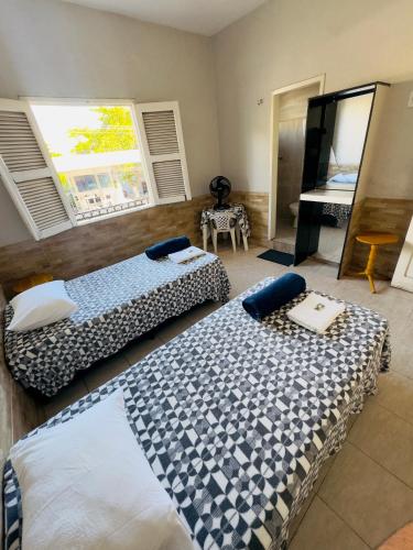 a bedroom with two beds and a mirror and a piano at Pousada Durma Bem in Tianguá
