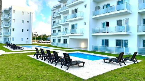 an apartment building with chairs and a swimming pool at Rheia Properties - SANTA FE in Sosúa