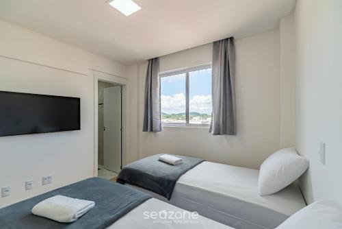 a bedroom with two beds and a flat screen tv at CII - Apartamentos a 900m da Praia em Porto Belo in Perequê