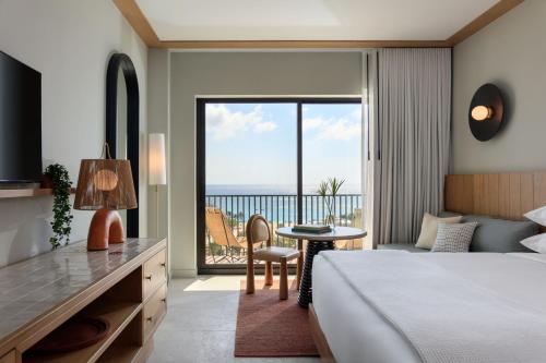 a hotel room with a bed and a table and a view at Hotel Indigo Grand Cayman by IHG in Grand Cayman