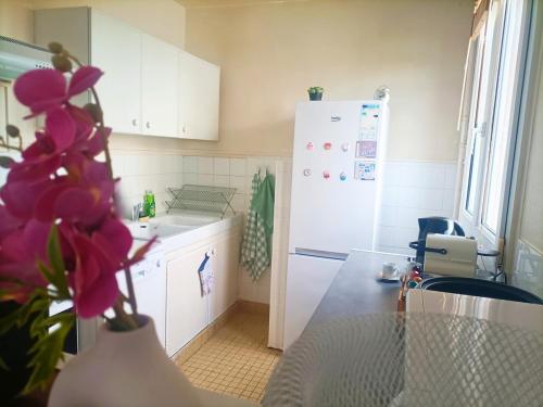 a kitchen with a white refrigerator and a vase with purple flowers at Le nid de Basch appartement près de Paris in Thiais