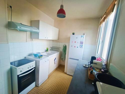 a small kitchen with white cabinets and a refrigerator at Le nid de Basch appartement près de Paris in Thiais
