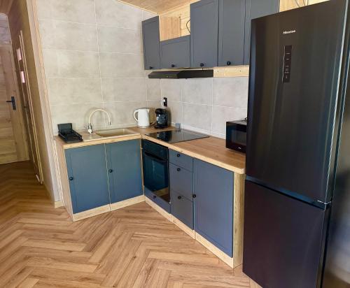 a kitchen with blue cabinets and a black refrigerator at Domek Konik Polny in Jastarnia