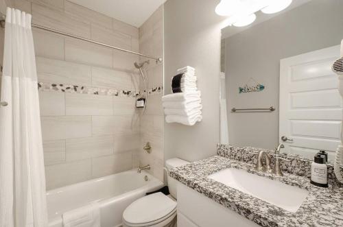 a white bathroom with a tub and a sink and a toilet at Blue Water Escape in Bolivar Peninsula