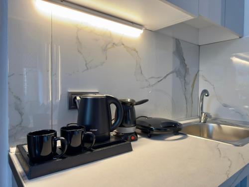 a kitchen counter with pots and pans and a sink at Celine Luxury Suites and Rooms in Olympiaki Akti