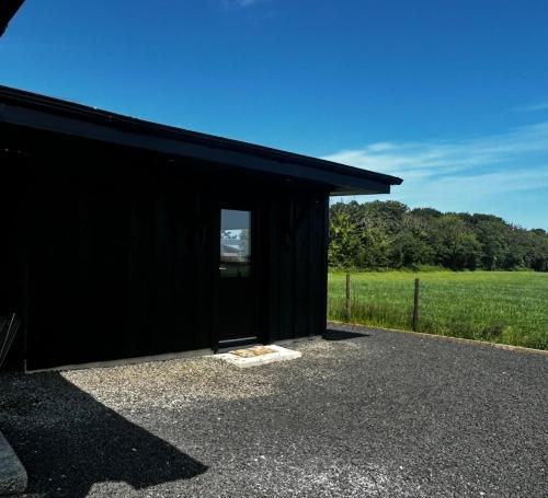 a black building with a window and a field at Springvale Lodge in Castlerock