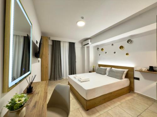 a bedroom with a bed and a desk and a television at Celine Luxury Suites and Rooms in Olympiaki Akti