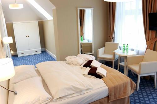 ポルチンズドロイにあるUzdrowisko Polczyn Willaのベッド、テーブル、椅子が備わるホテルルームです。