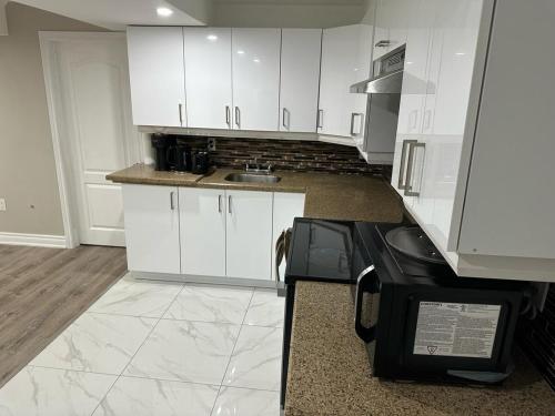 a kitchen with white cabinets and a stove at Cozy 1 Bedroom Apartment in Brampton