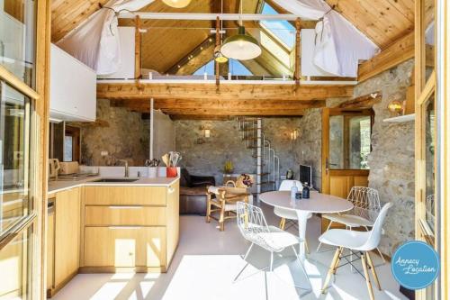 une cuisine ouverte et une salle à manger avec une table et des chaises dans l'établissement Le Grenier 4 - Mazot Savoyard, à Talloires