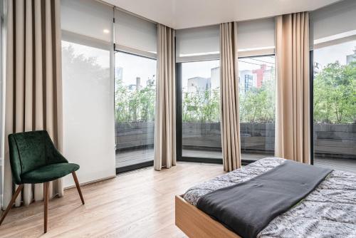 a bedroom with a bed and a chair and windows at Insurgentes APT Private Balcony, Roof Lounge in Mexico City