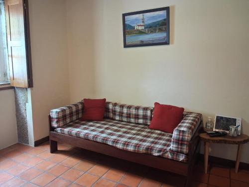 a couch with two red pillows sitting in a room at Cottage - Vitorino dos Piães in Vitorino dos Piães