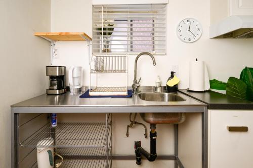 a kitchen counter with a sink and a clock on the wall at Charming Basement Suite with Private Entrance Near Subway, Koreatown & UofT in Toronto