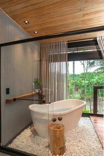 a bath tub in a bathroom with a large window at Green Barn Hotel & Bistro in Urubici