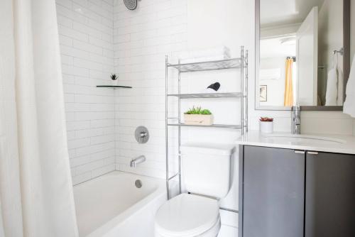 a white bathroom with a toilet and a sink at THE MANDO, walkable to PonceCityMarket in Atlanta