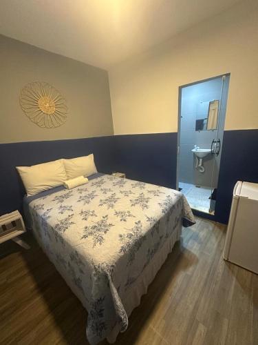 a bedroom with a bed and a bathroom with a sink at Hostel Barra in Salvador