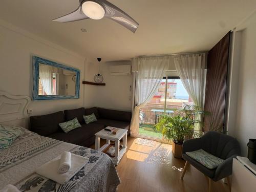 a bedroom with a bed and a couch and a window at SWEET HOME BENALMADENA Estudio para NO FUMADORES con vistas al mar y excelente conexion wifi NON SMOKING studio with sea views and excellent WiFi Enjoy plenty of morning sun in Benalmádena
