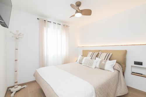 a bedroom with a white bed with a ceiling fan at Estilo y relax junto al mar in Santa Pola