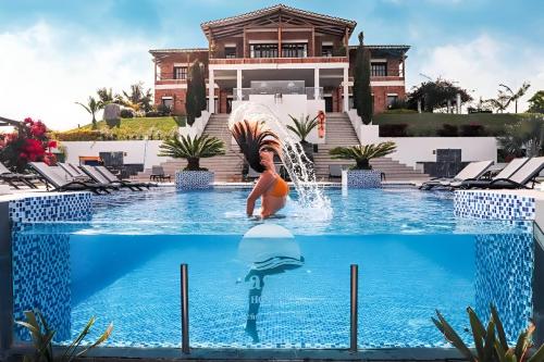 a woman in a pool with a dolphin in front of a house at Hotel La Magdalena Adult Only in Guatapé