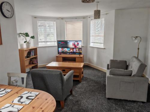 a living room with a tv and two chairs and a table at 2 bed Flat near Corby Town Centre in Corby