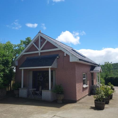 una pequeña casa de ladrillo rojo con porche en Apple Blossom Cottage, en New Ross