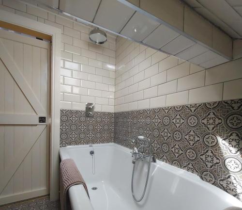a bathroom with a bath tub with a shower at Apple Blossom Cottage in New Ross