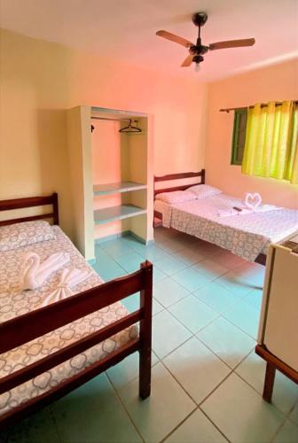 a room with two beds and a ceiling fan at Suítes Casa Rosada in Ubatuba