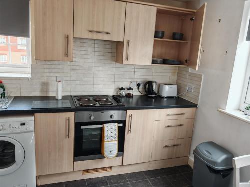 a kitchen with wooden cabinets and a stove top oven at 2 bed Flat near Corby Town Centre in Corby